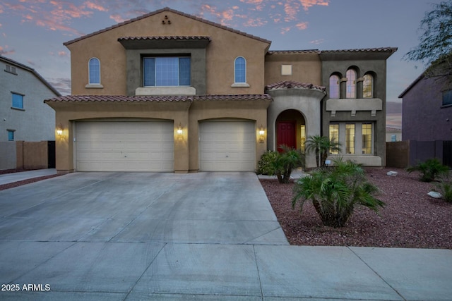 mediterranean / spanish-style house featuring a tiled roof, concrete driveway, and a garage