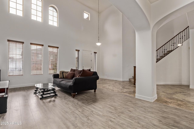 living area with stairway, wood finished floors, baseboards, and arched walkways