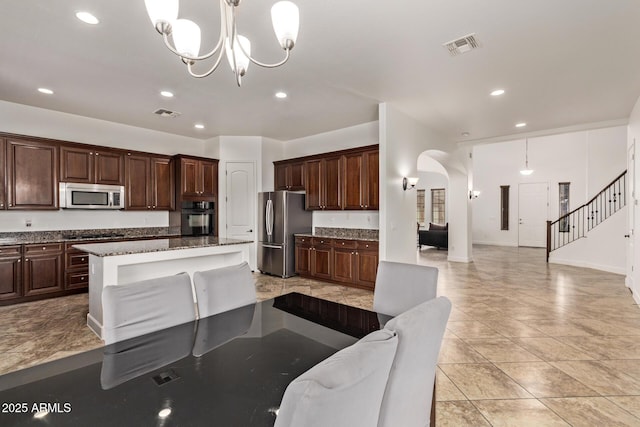 kitchen featuring a chandelier, open floor plan, arched walkways, and stainless steel appliances