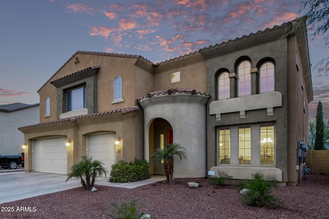 mediterranean / spanish-style house with concrete driveway, a tiled roof, an attached garage, and stucco siding