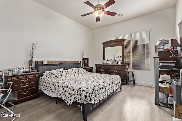 bedroom with visible vents, baseboards, wood finished floors, and a ceiling fan