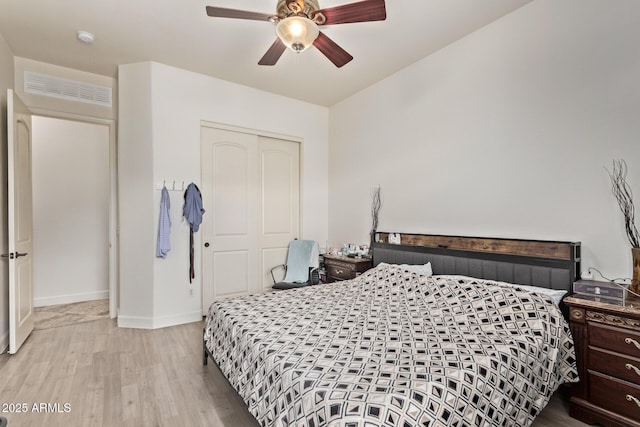 bedroom featuring wood finished floors, visible vents, baseboards, ceiling fan, and a closet