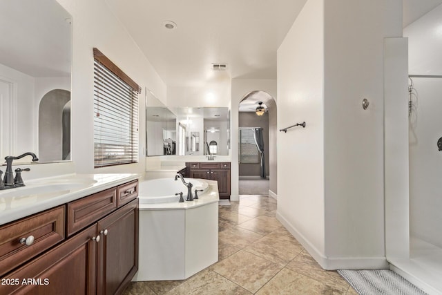 bathroom with a ceiling fan, visible vents, two vanities, a sink, and a garden tub