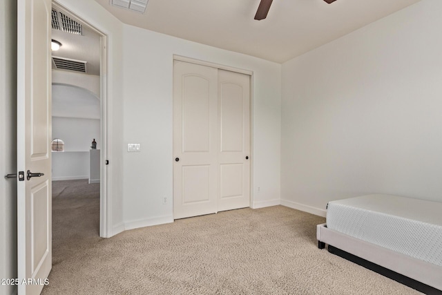 carpeted bedroom with visible vents, baseboards, a closet, and ceiling fan