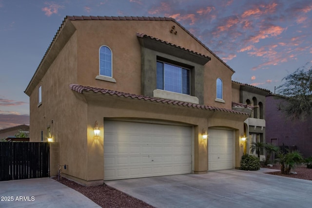 mediterranean / spanish-style house with stucco siding, driveway, a tile roof, and a garage