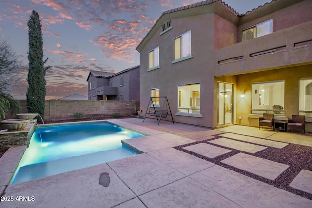 pool at dusk featuring a patio area, a fenced in pool, and fence