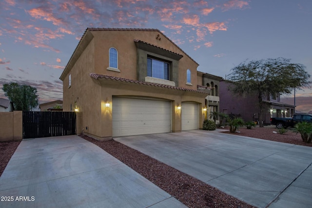 mediterranean / spanish-style house with stucco siding, a garage, driveway, and a tile roof