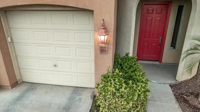 doorway to property with stucco siding and a garage