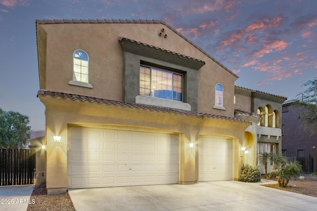 mediterranean / spanish-style house featuring a garage, concrete driveway, and stucco siding