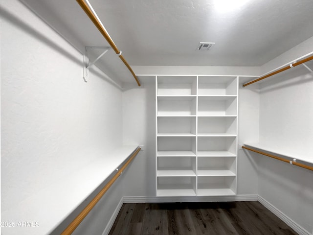 spacious closet with dark hardwood / wood-style flooring