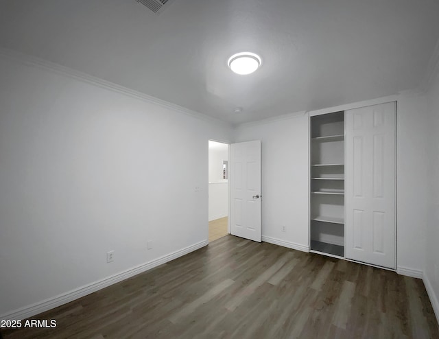 unfurnished bedroom featuring dark wood-type flooring and ornamental molding