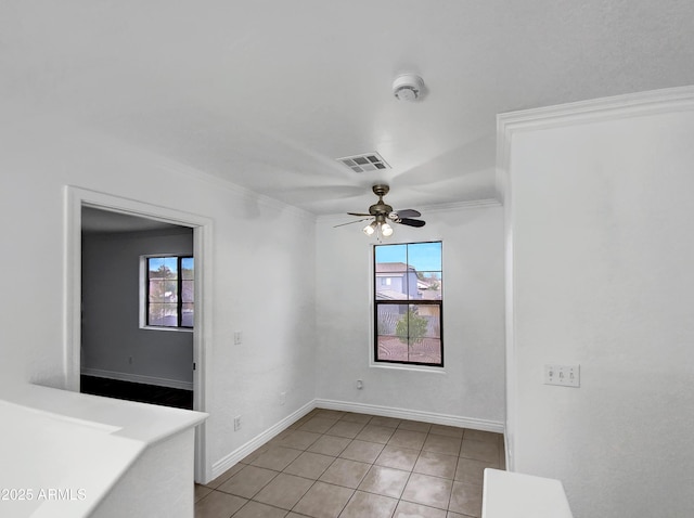 tiled spare room featuring ornamental molding, a wealth of natural light, and ceiling fan