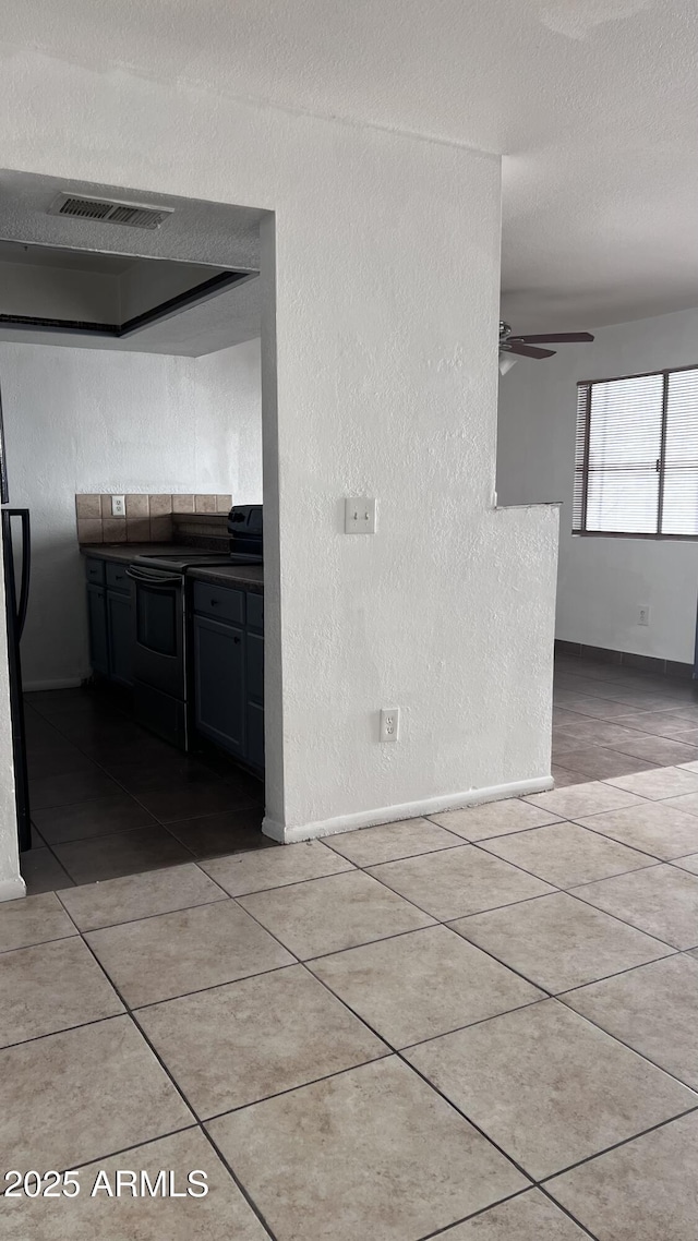 interior space featuring ceiling fan, light tile patterned floors, and a textured ceiling