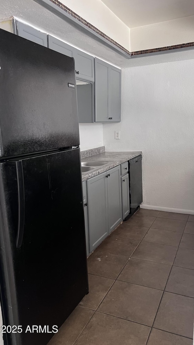 kitchen featuring gray cabinets, sink, dark tile patterned flooring, and black appliances