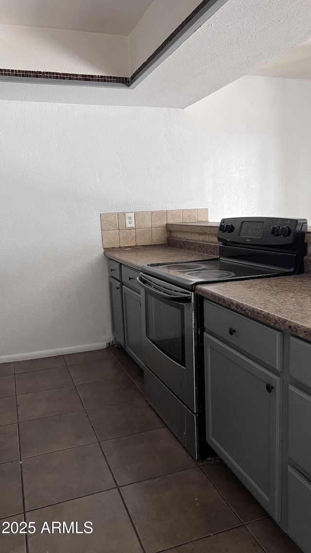 kitchen featuring range with electric stovetop, dark tile patterned flooring, and gray cabinetry