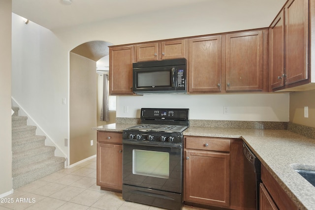 kitchen with arched walkways, baseboards, black appliances, brown cabinetry, and light tile patterned floors