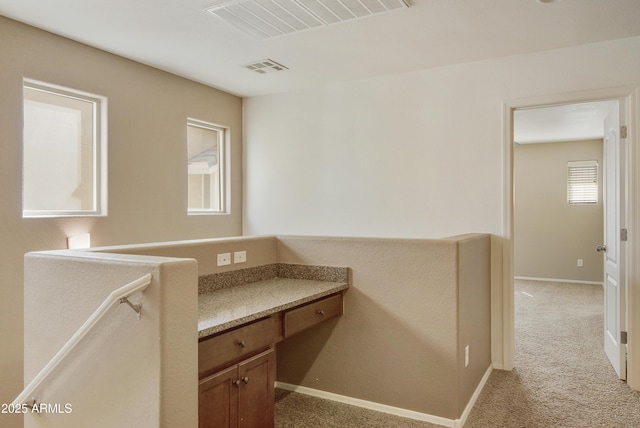 corridor featuring light colored carpet, baseboards, and visible vents