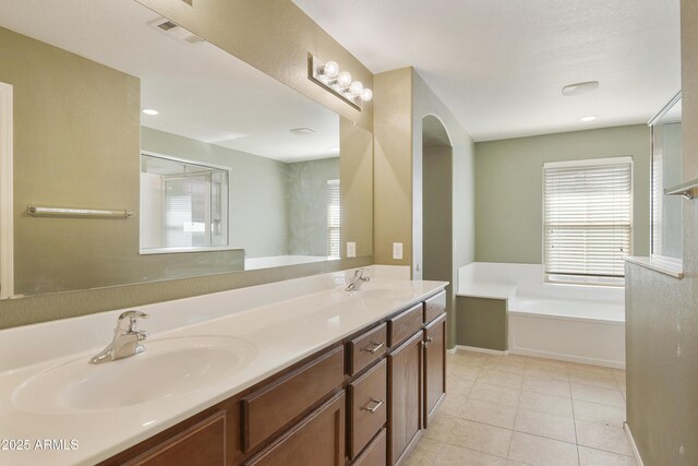 bathroom featuring a garden tub, tile patterned flooring, a sink, and visible vents