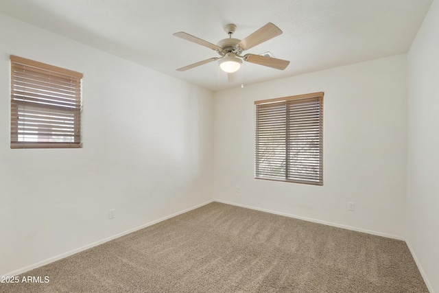 carpeted empty room featuring a ceiling fan and baseboards