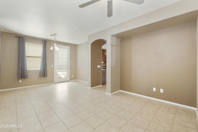 empty room featuring arched walkways, baseboards, light tile patterned floors, and ceiling fan with notable chandelier