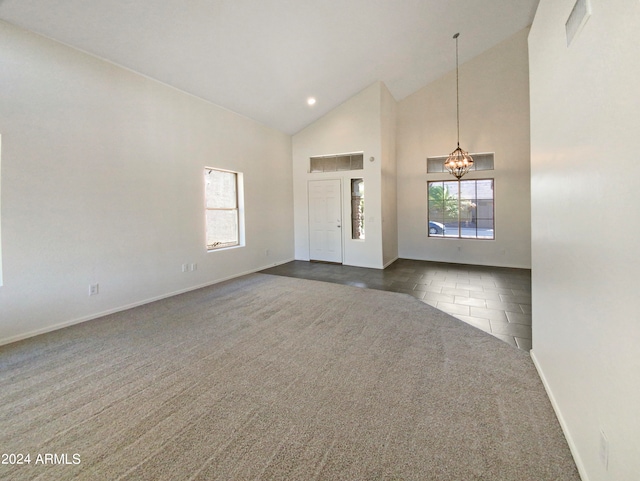 entrance foyer with a chandelier, high vaulted ceiling, dark tile patterned floors, and a wealth of natural light