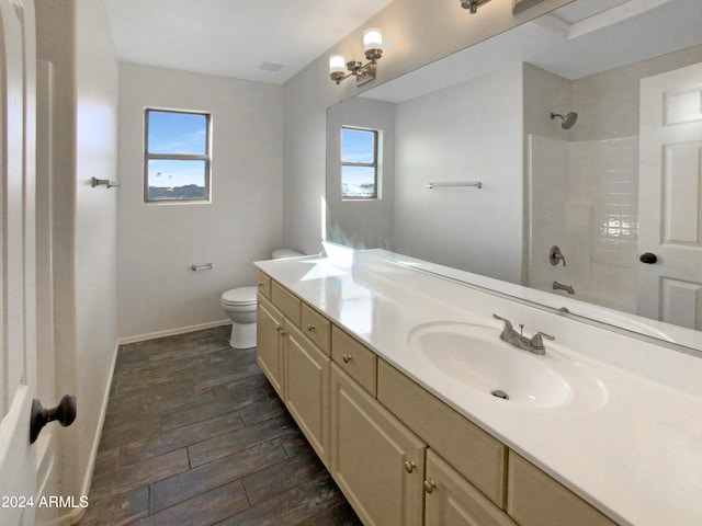 bathroom featuring vanity, toilet, a tile shower, and plenty of natural light