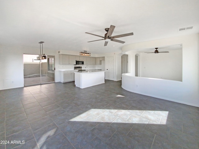 unfurnished living room featuring dark tile patterned flooring, ceiling fan, and sink