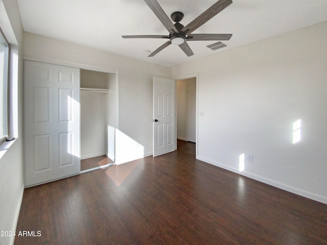 unfurnished bedroom featuring ceiling fan, multiple windows, and dark hardwood / wood-style flooring