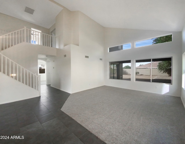 unfurnished living room featuring high vaulted ceiling and dark carpet