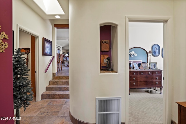 hallway with a skylight and carpet floors