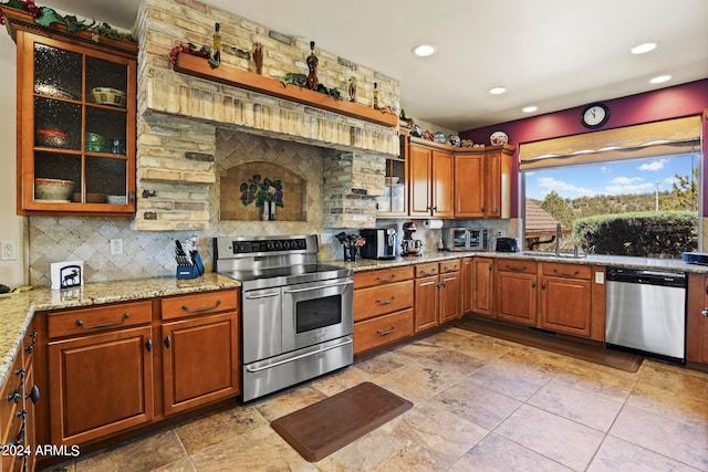 kitchen with light stone countertops, stainless steel appliances, tasteful backsplash, and sink