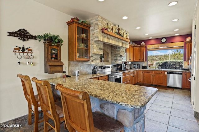 kitchen featuring stainless steel appliances, decorative backsplash, kitchen peninsula, and a breakfast bar area