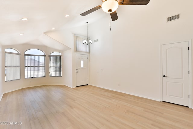 unfurnished living room with ceiling fan with notable chandelier, lofted ceiling, and light wood-type flooring