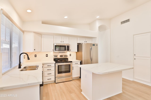 kitchen featuring light stone countertops, a center island, white cabinetry, stainless steel appliances, and sink