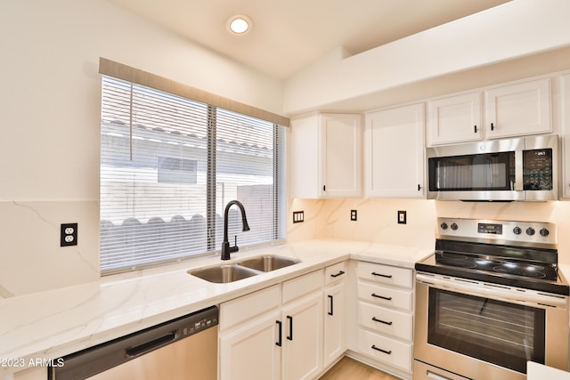 kitchen featuring light stone countertops, appliances with stainless steel finishes, white cabinets, and sink