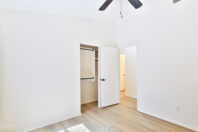 unfurnished bedroom with light wood-type flooring, ceiling fan, and a closet