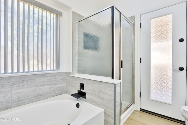 bathroom featuring toilet, hardwood / wood-style flooring, and separate shower and tub