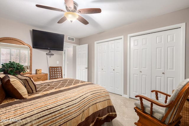 bedroom with ceiling fan, light tile patterned flooring, and two closets