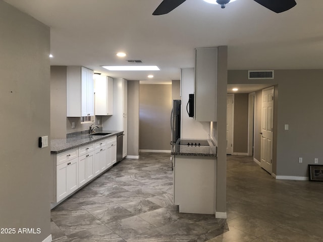 kitchen featuring dark stone counters, black appliances, sink, ceiling fan, and white cabinetry