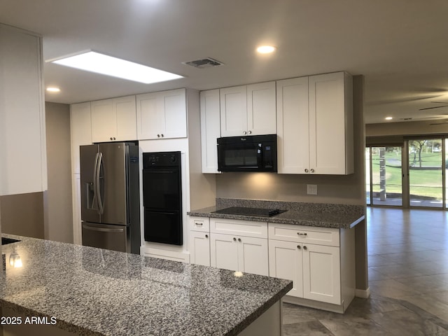 kitchen with black appliances, ceiling fan, white cabinets, and dark stone counters