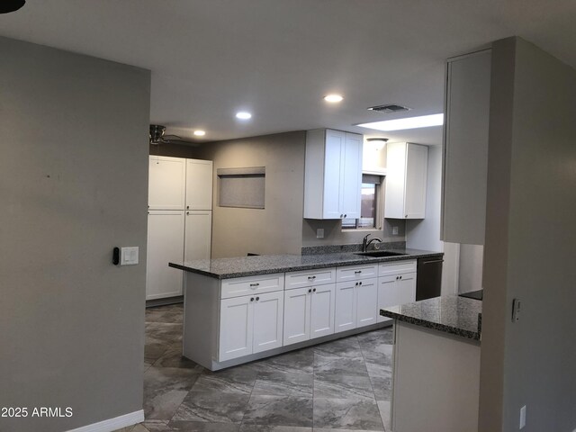 kitchen with kitchen peninsula, ceiling fan, sink, dishwasher, and white cabinetry