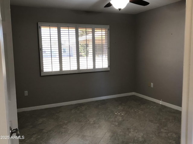 unfurnished room featuring dark tile patterned floors and ceiling fan