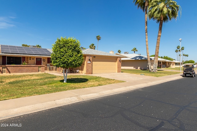 single story home featuring solar panels, a garage, and a front lawn