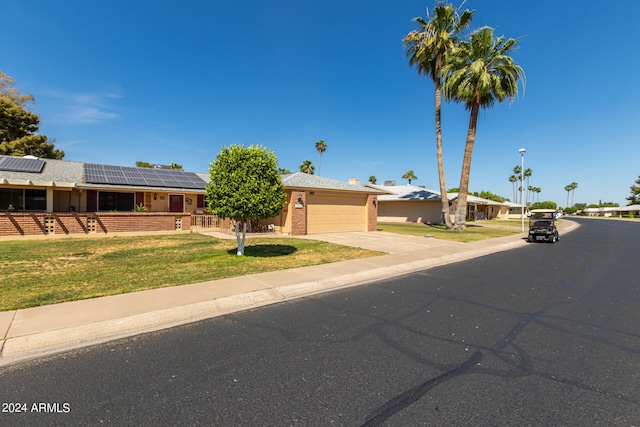 ranch-style home featuring a front lawn, a garage, and solar panels