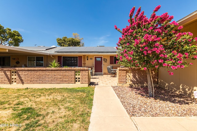 ranch-style house featuring solar panels and a front yard