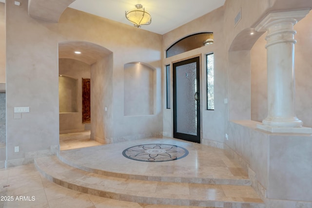 entrance foyer featuring arched walkways, decorative columns, and baseboards