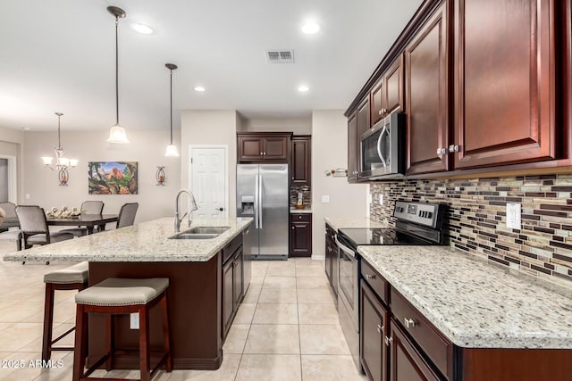 kitchen with sink, an island with sink, decorative light fixtures, light tile patterned flooring, and stainless steel appliances