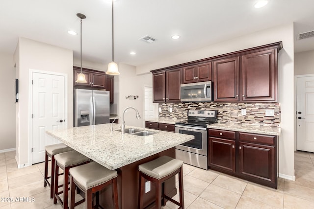 kitchen featuring pendant lighting, a center island with sink, sink, decorative backsplash, and stainless steel appliances