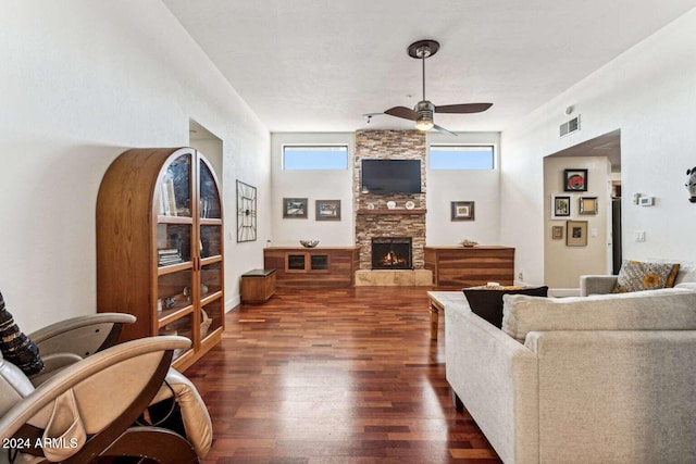 living room featuring a stone fireplace, dark hardwood / wood-style floors, and ceiling fan