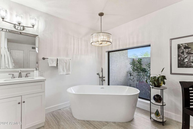 bathroom featuring an inviting chandelier, vanity, hardwood / wood-style floors, and a tub to relax in